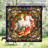 Decorative blanket with a white horse in the center, surrounded by flowers and animals, with a garden scene in the background.