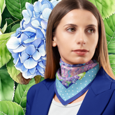 Woman wearing a floral silk scarf with blue hydrangeas and green leaves in the background