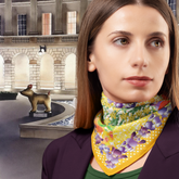 Woman wearing a colourful yellow scarf with a building and sculpture in the background