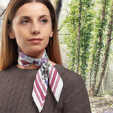 Woman wearing a floral and striped scarf outdoors with trees in the background
