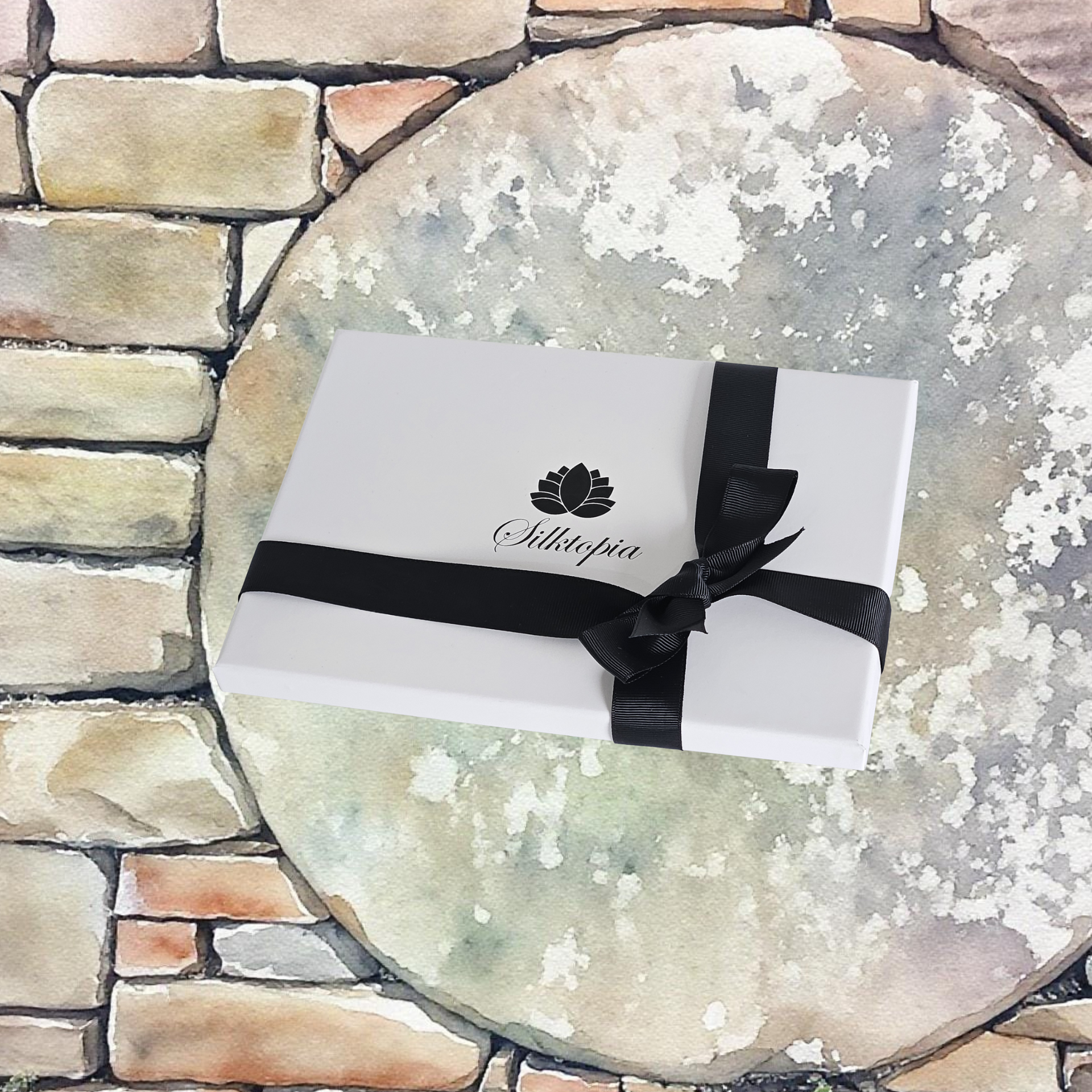 White gift box with black ribbon and Silktopia's Gift Box on a stone surface