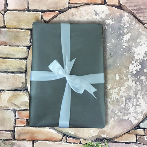 Gift wrapped in green paper with a white ribbon on a stone surface.