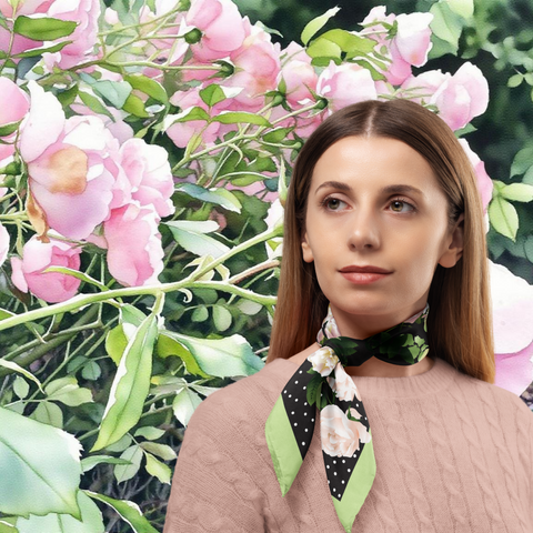 Woman wearing a silk twill rose scarf with floral design in front of pink flowers and green leaves